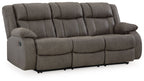 Gunmetal reclining sofa with tufted back, padded headrest, and arm recliner