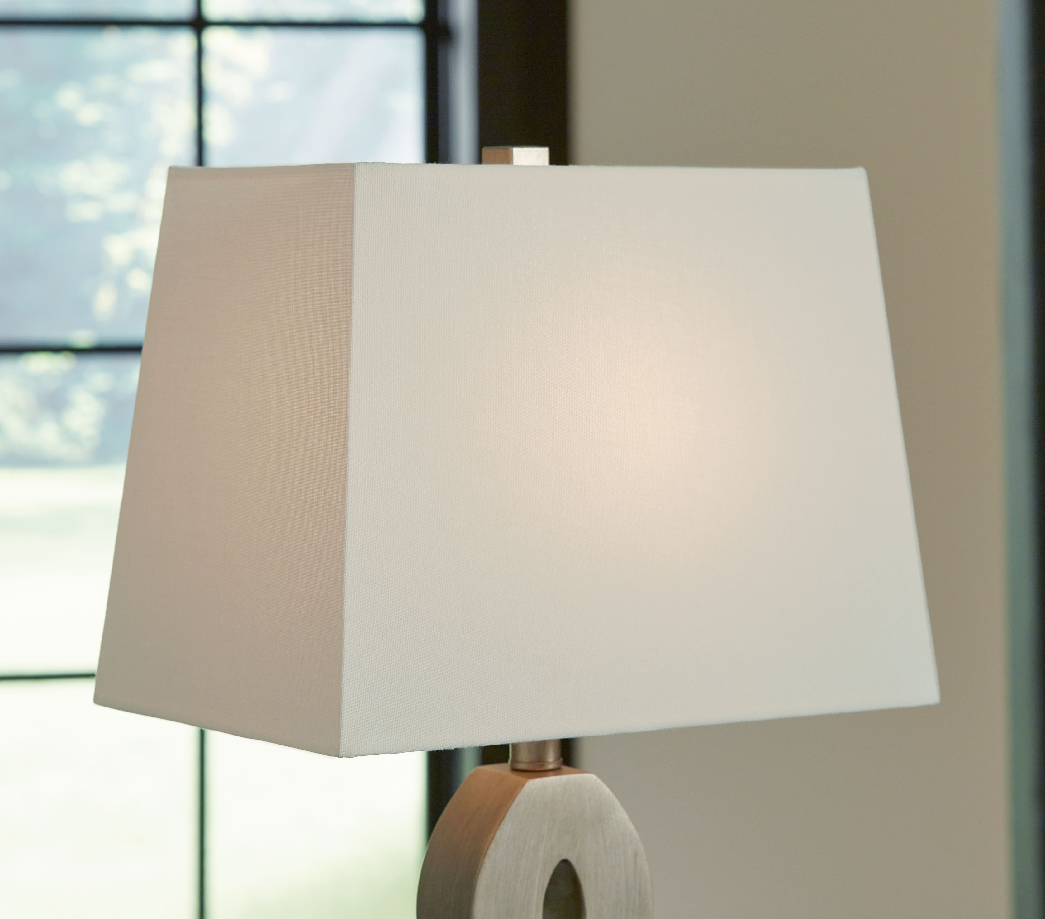 Table lamp with off-white drum shade and top of gray cutout base
