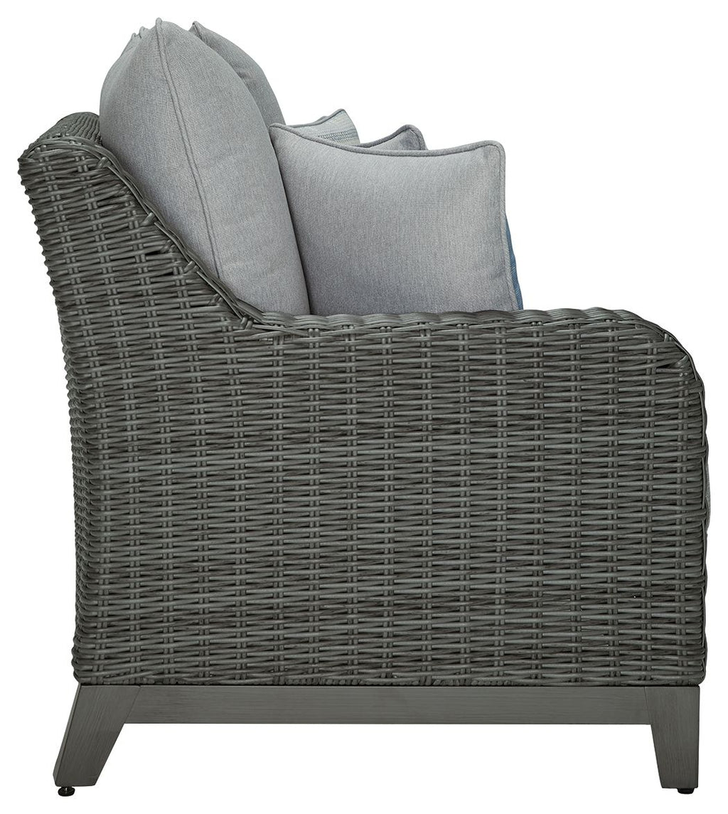 Gray woven outdoor sofa chair with arm cushions and blue accent pillow