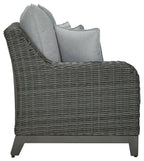 Gray woven outdoor sofa chair with arm cushions and blue accent pillow
