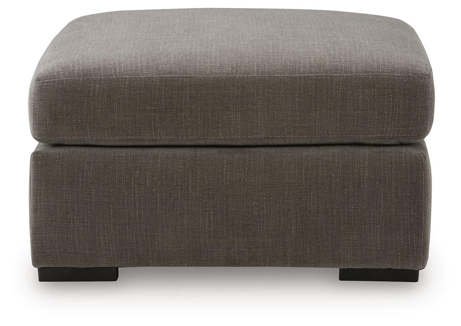 Gray upholstered accent ottoman with thick padded top and front-facing block legs