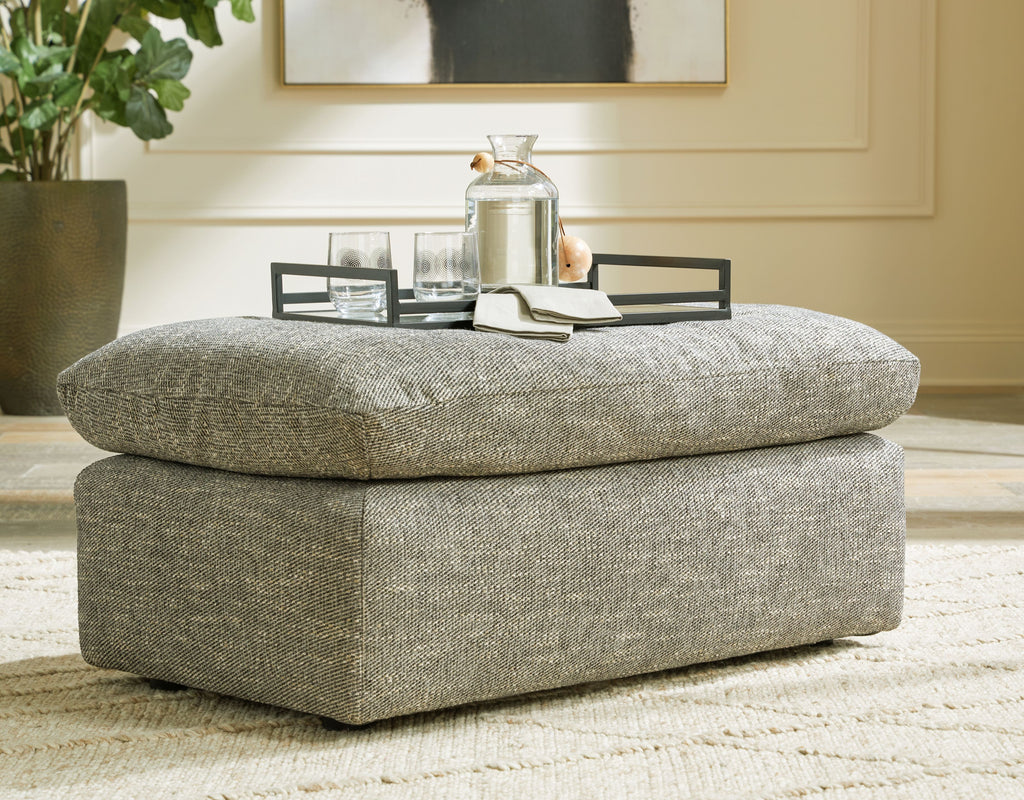 Gray upholstered ottoman with rounded lid and blocky base