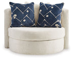 Ivory round accent chair with two navy patterned pillows centered on the cushioned seat