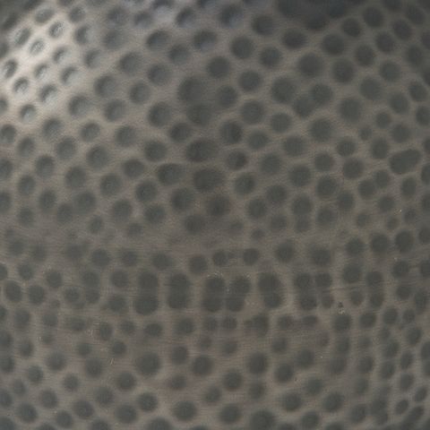 Dark gray dimpled hammered ceramic surface of the vase