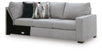 Gray fabric sofa with corner wedge, cushioned armrests, patterned and dark throw pillows, black legs