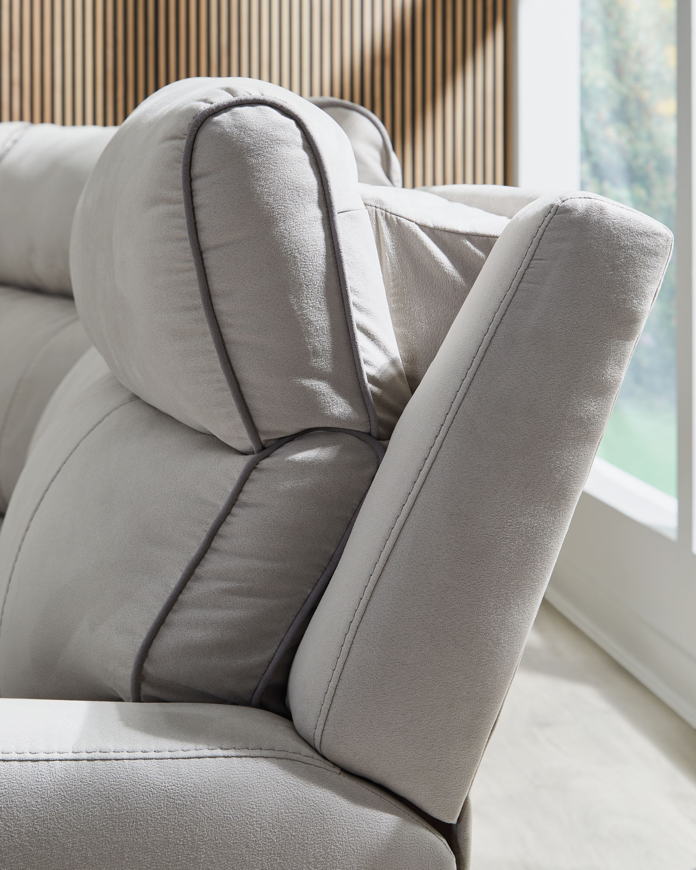 Light gray reclining sofa armrest with split cushion and rounded corner