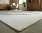 Rug with dark wave stripe center and cream field, textured low pile corner