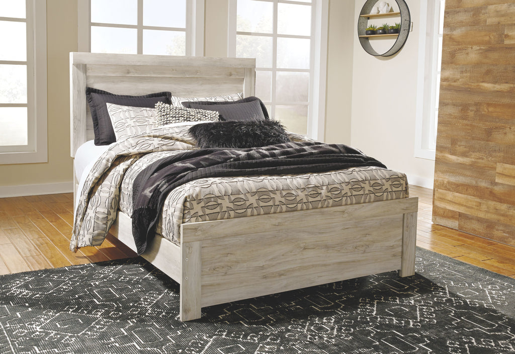 Panel bed with beige headboard and layered gray-and-beige patterned comforter set.
