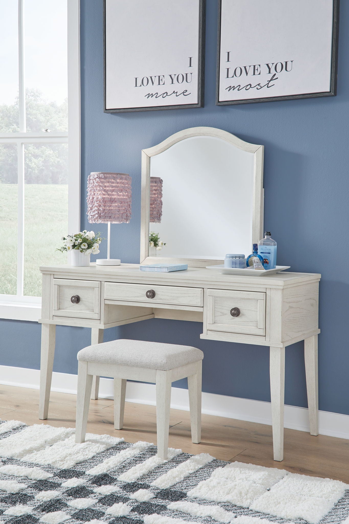 Antique white mirrored vanity with four drawers and an upholstered stool