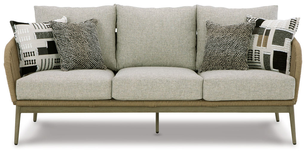 Beige wicker sofa with three seat cushions and patterned throw pillows