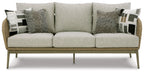 Beige wicker sofa with three seat cushions and patterned throw pillows