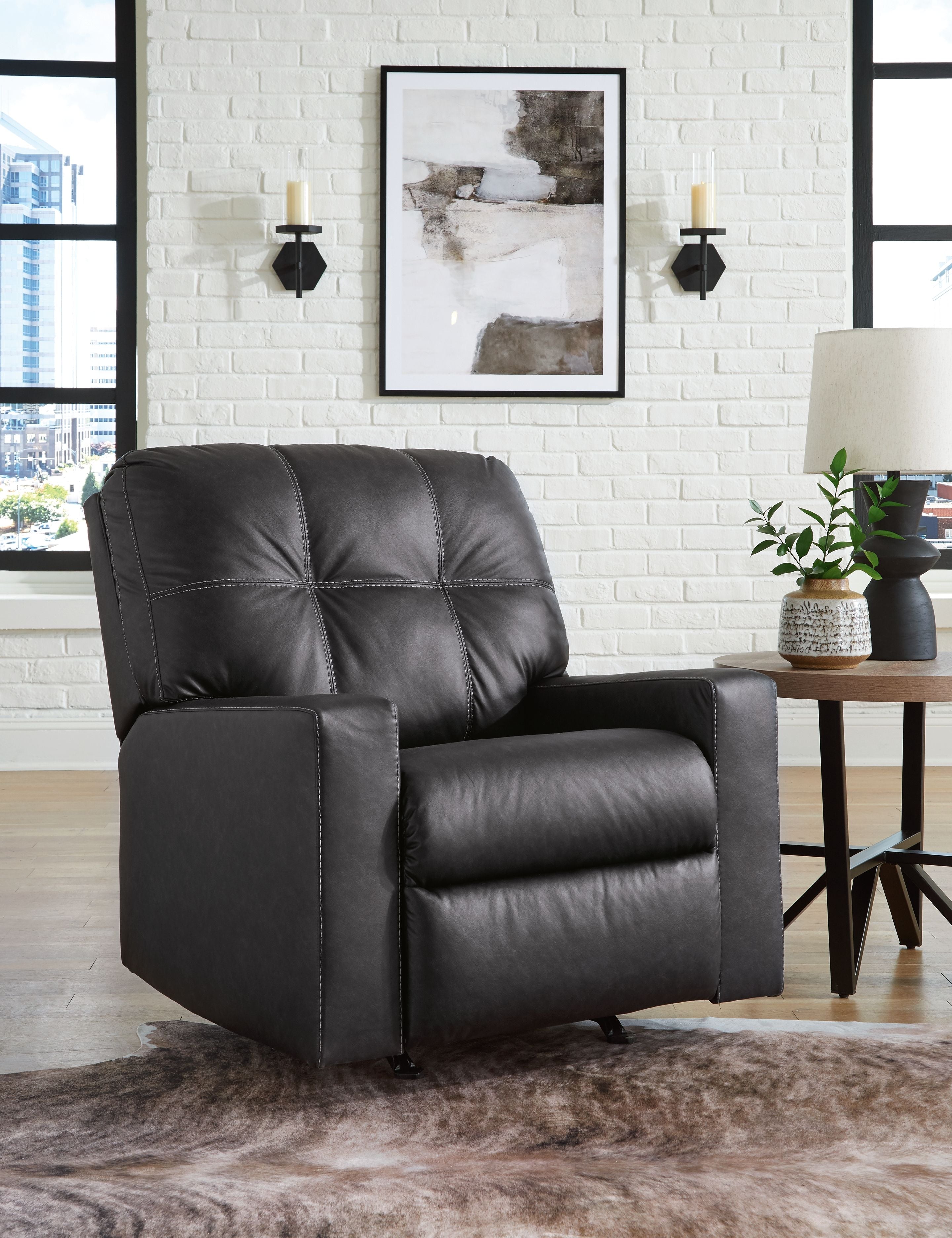 Dark gray rocker recliner with padded arms, tufted back, and cushioned seat