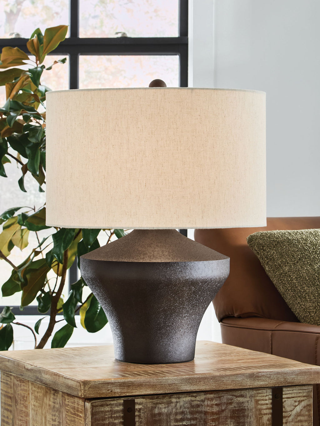 Distressed brown metal table lamp on wood surface with beige fabric shade