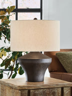 Distressed brown metal table lamp on wood surface with beige fabric shade