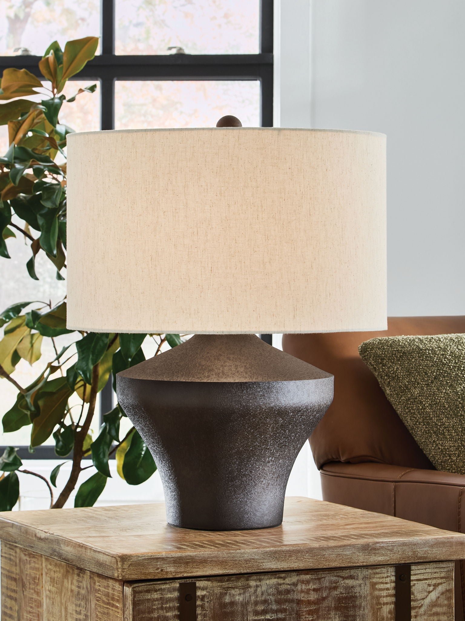 Distressed brown metal table lamp on wood surface with beige fabric shade