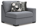 Gray upholstered chaise corner chair with rounded back and large patterned back pillow