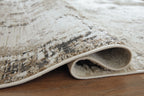 Close-up of distressed gray-and-beige area rug edge with low pile and beige border.