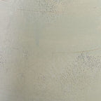 Cream speckled glaze close-up on ceramic vase with subtle seam lines.