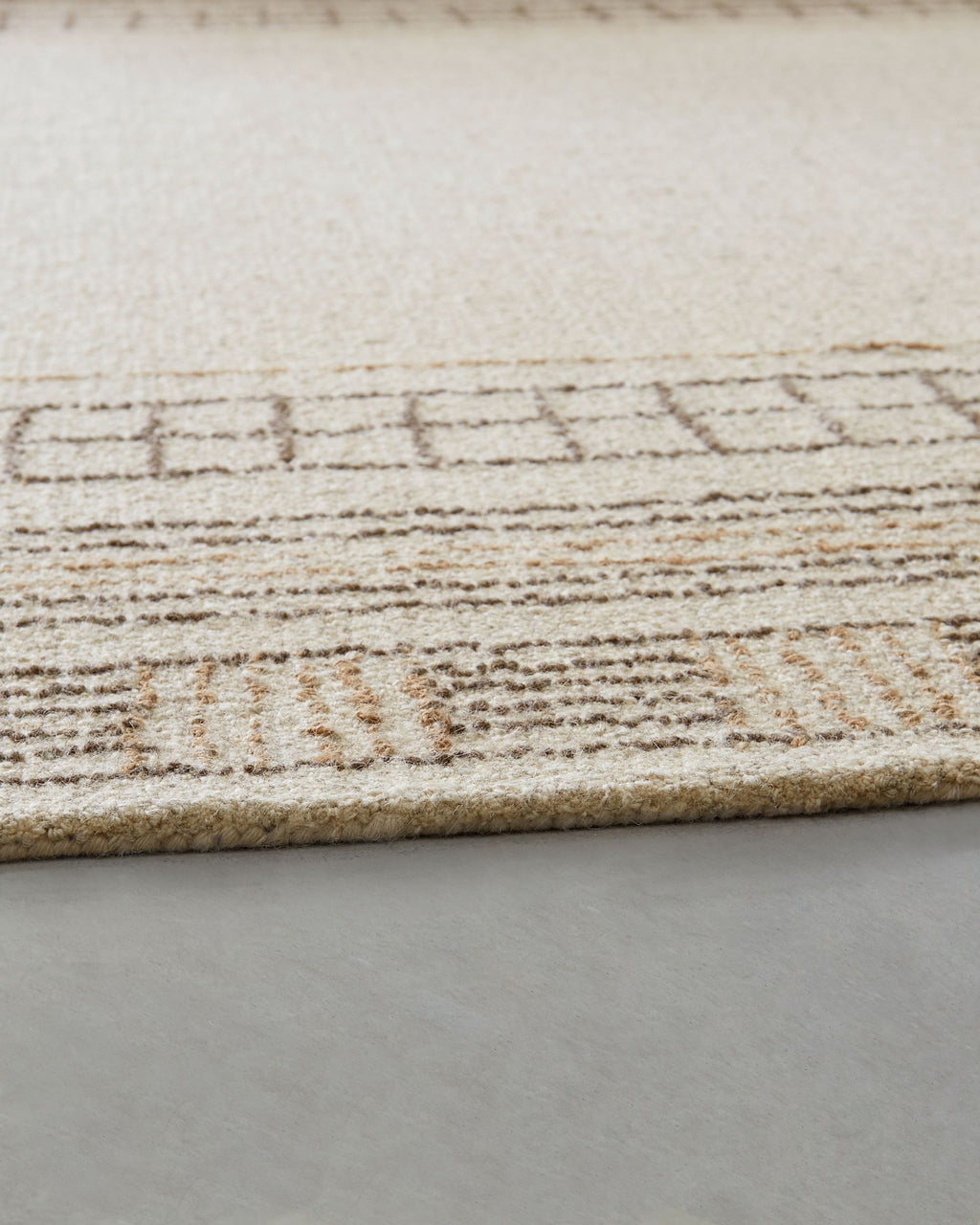 Beige rug edge with stitched geometric border pattern
