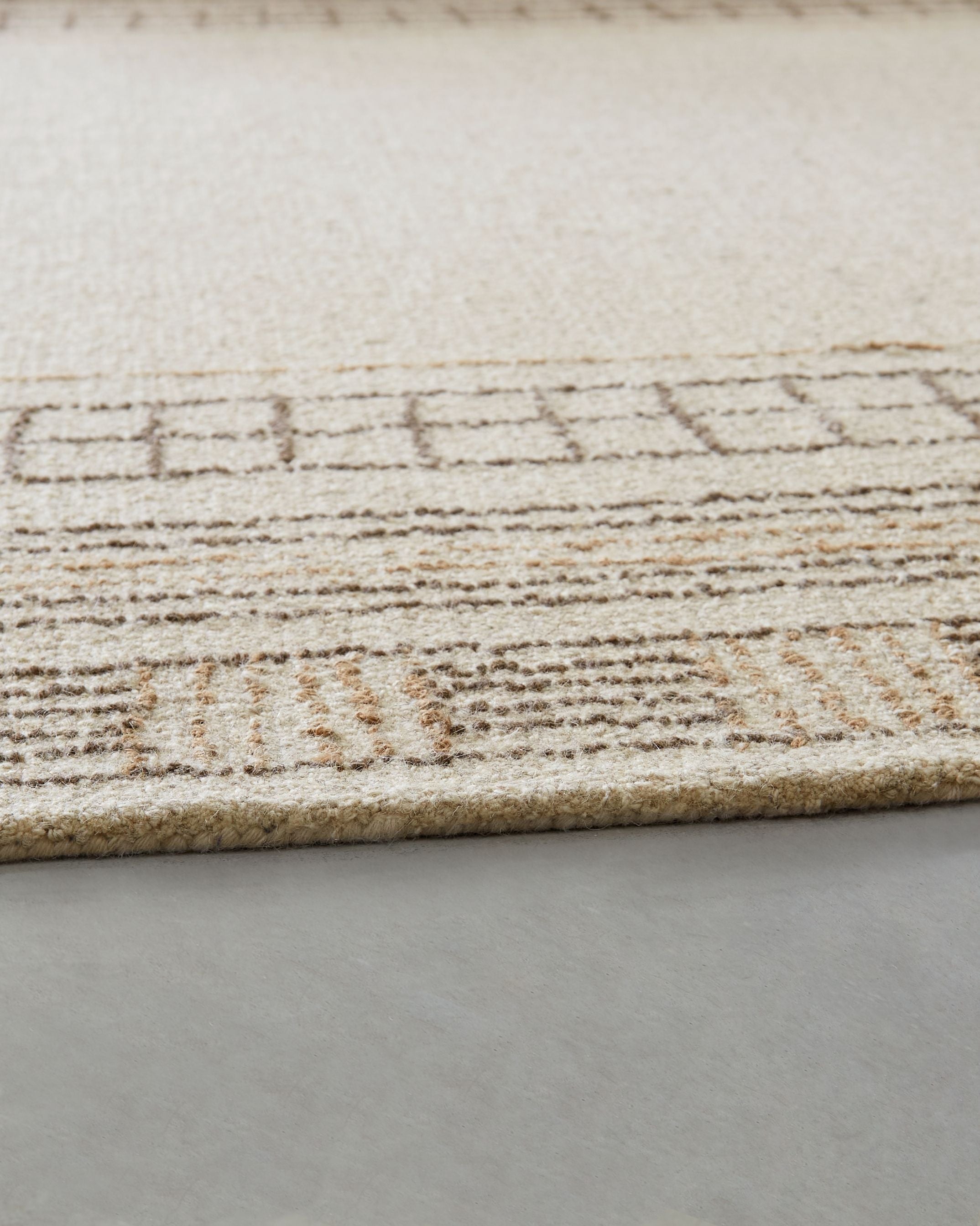 Beige rug edge with stitched geometric border pattern