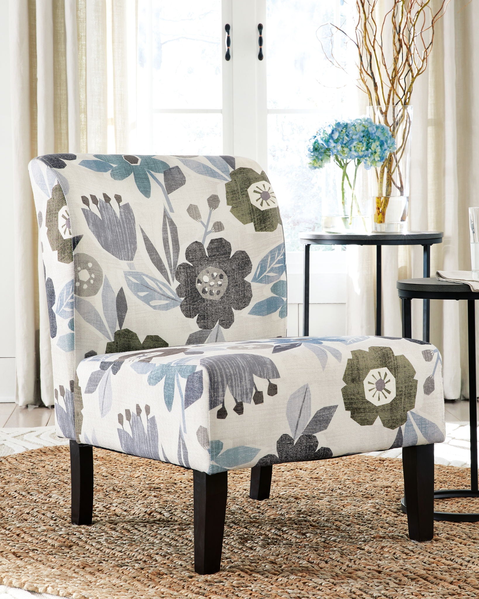 Accent chair with blue-gray floral upholstery and dark wooden legs, upholstered arms.