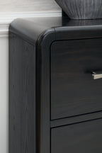 Black dresser corner with curved top edge and metal drawer pull