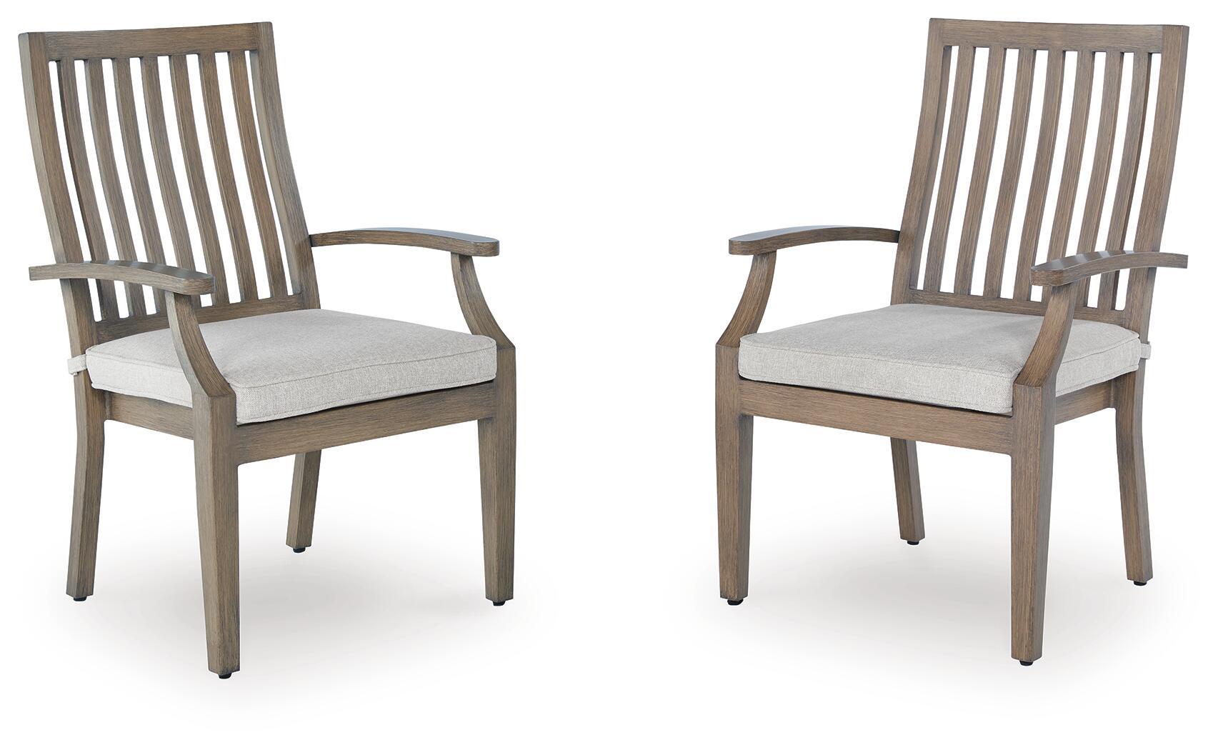 Set of two wooden arm chairs with slatted backs and light beige seat cushions.