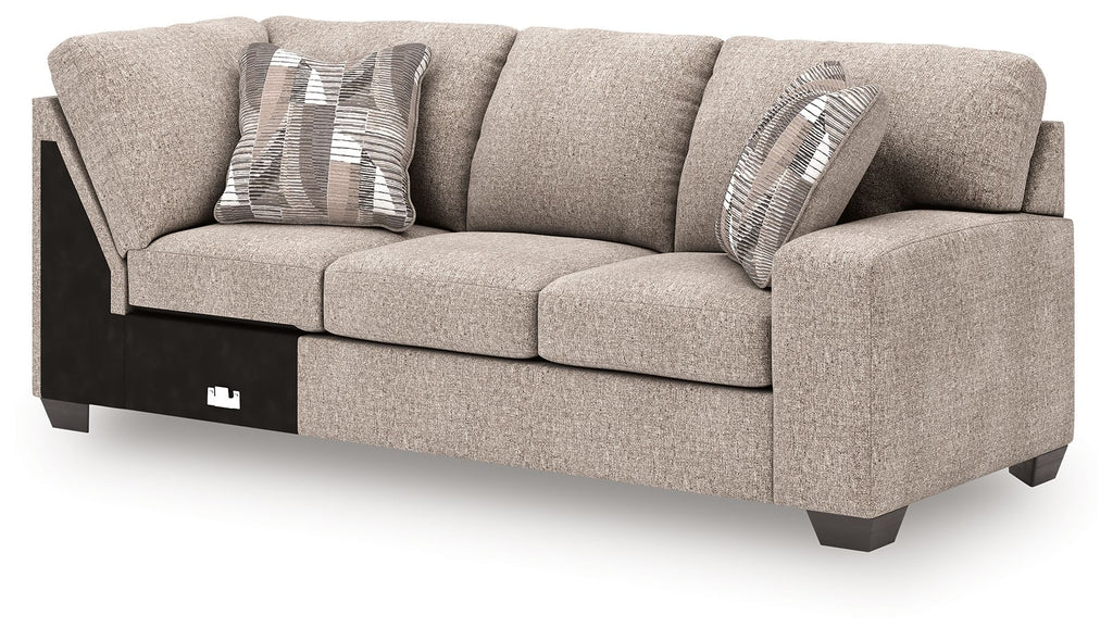 Beige fabric RAF sofa with corner wedge and three seat cushions, two striped pillows.