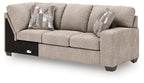 Beige fabric RAF sofa with corner wedge and three seat cushions, two striped pillows.