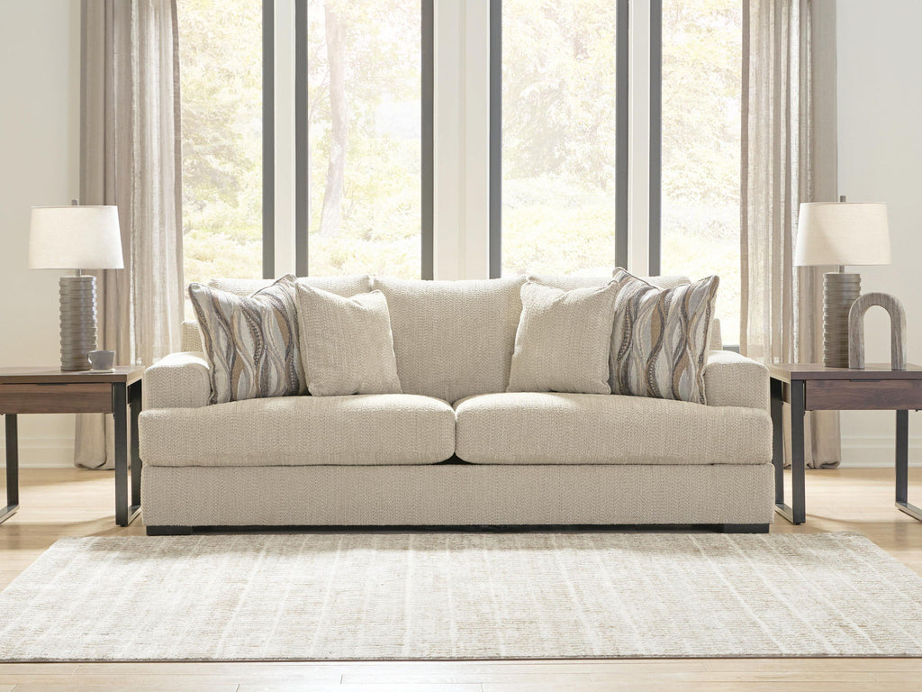Beige upholstered sofa with striped accent pillows and three back cushions