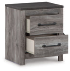 Two-drawer night stand with one drawer open, gray woodgrain and black metal pulls.