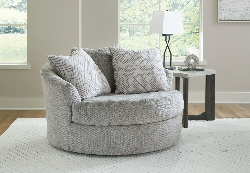 Oversized swivel accent chair in cement gray with patterned throw pillows and wide rounded arms