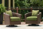 Set of two brown wicker swivel lounge chairs with green cushions and patterned back pillows