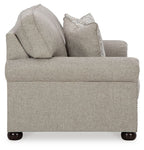 Light gray-beige loveseat from side angle with two patterned accent pillows
