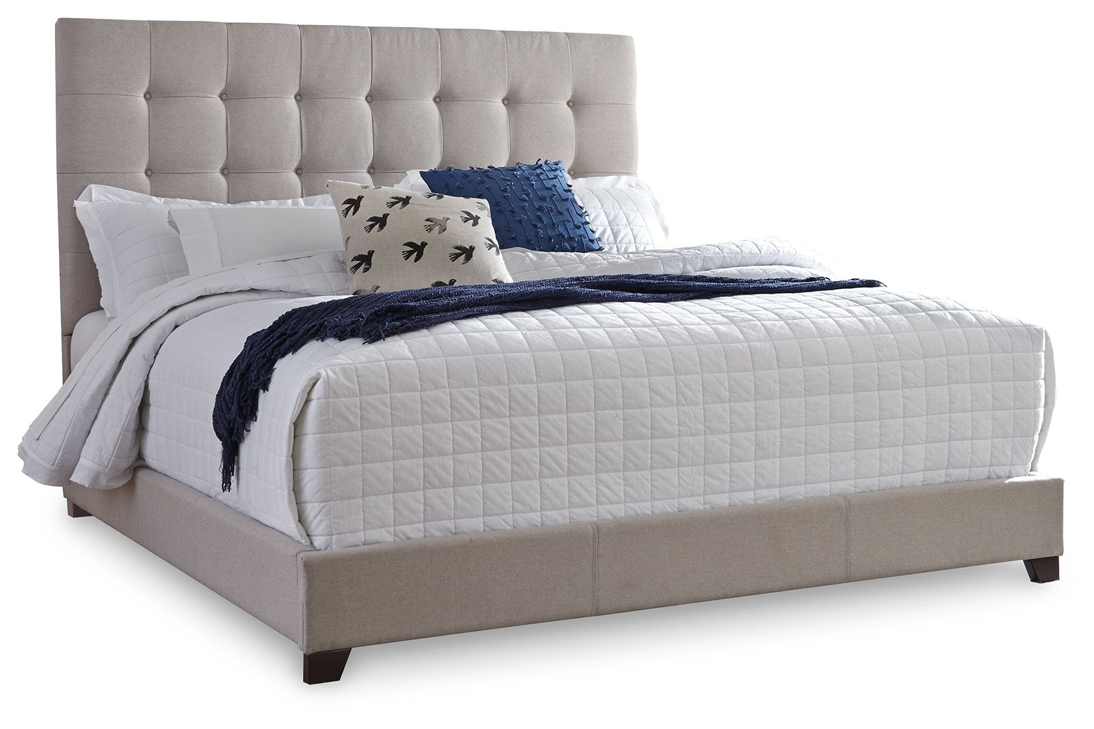 Dolante upholstered bed with beige tufted headboard, white quilt and navy throw