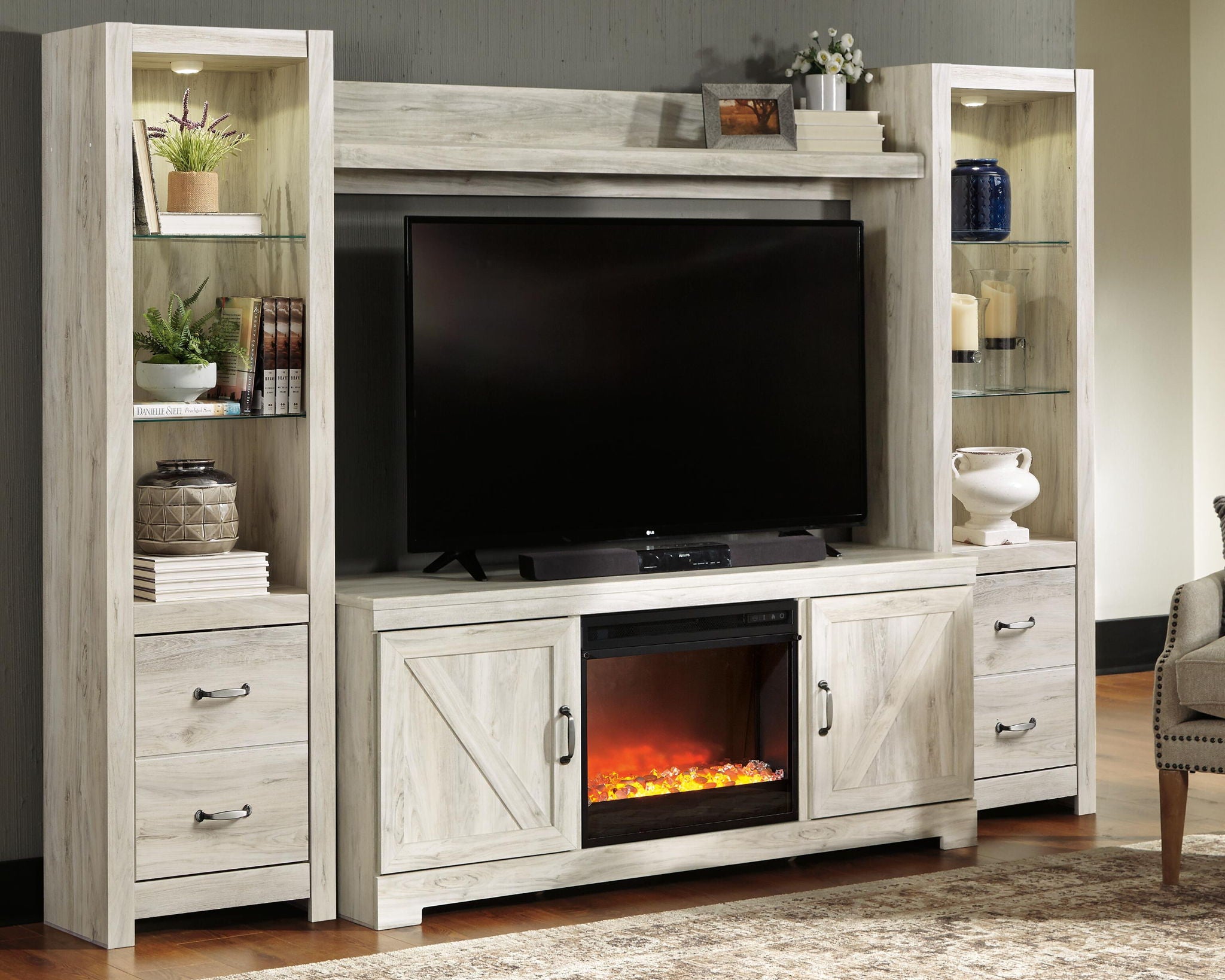 Beige entertainment center with TV cabinet, open shelves, and glass-front electric fireplace