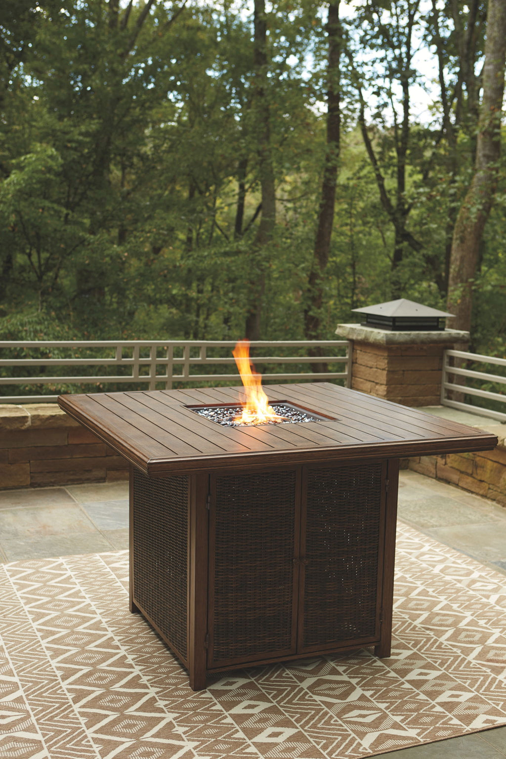 Outdoor fire pit table set with flame burning in a square woven tabletop