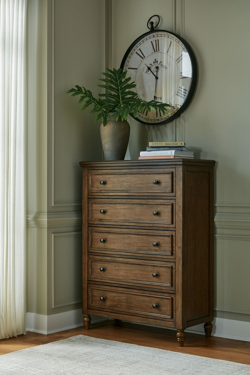 Brown five-drawer chest with metal knobs, framed drawer fronts, and tapered legs