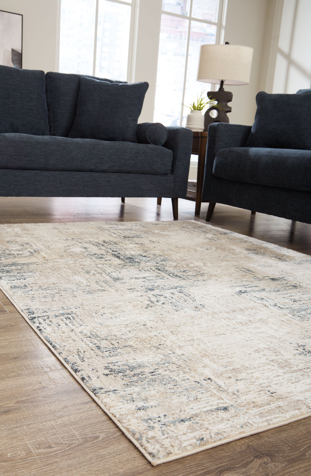 Cream abstract area rug with blue-gray distressed pattern in a living room setting.