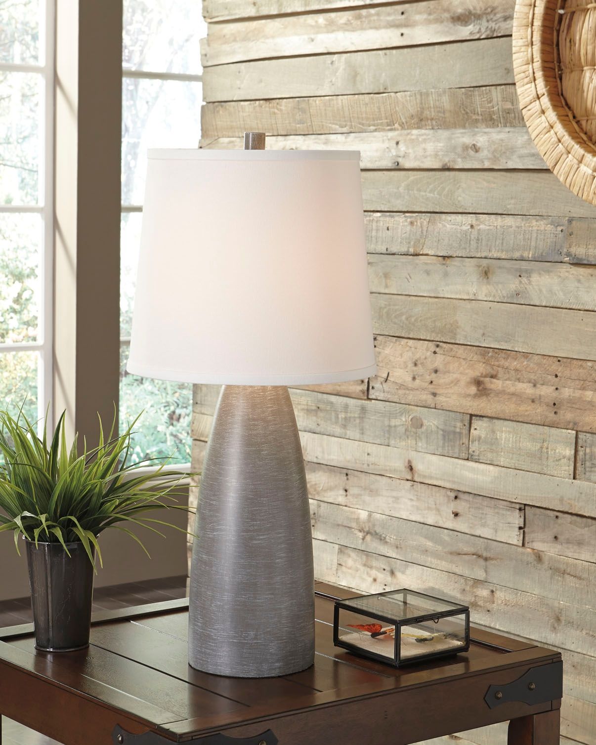 Gray poly table lamp with white fabric drum shade on a side table