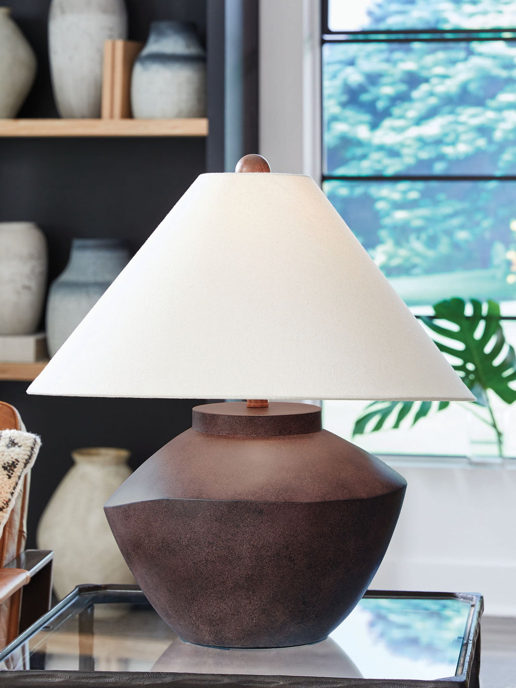 Antique brown table lamp with beige shade on glass-topped surface