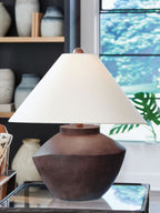 Antique brown table lamp with beige shade on glass-topped surface