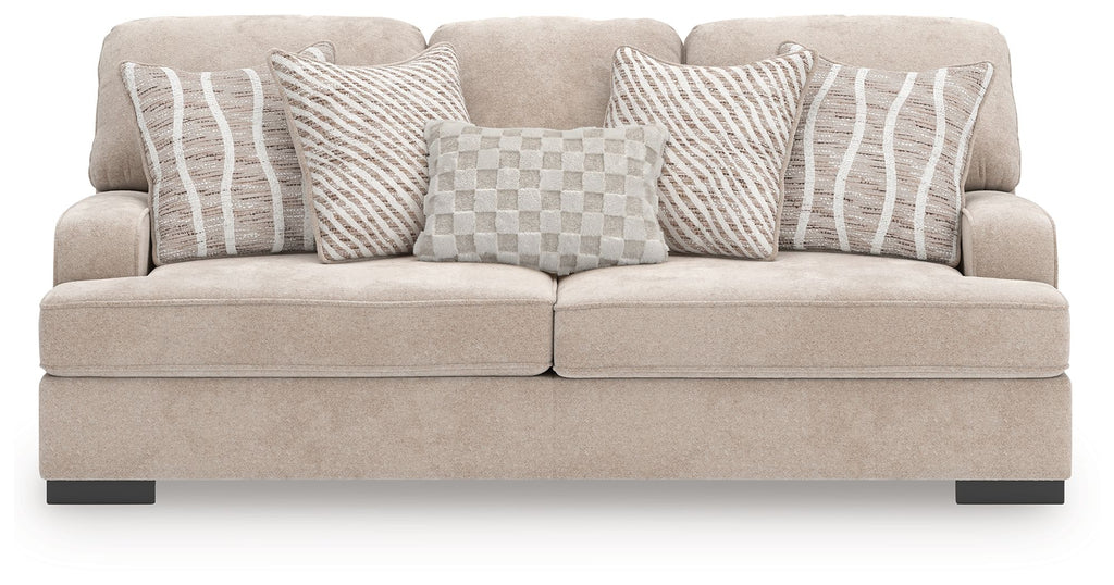 Taupe upholstered sofa with four patterned pillows: striped and checkered designs