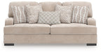 Taupe upholstered sofa with four patterned pillows: striped and checkered designs