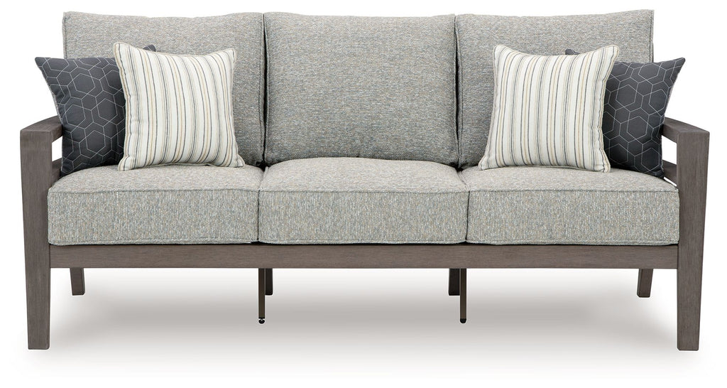 Gray outdoor sofa with three seat sections and two striped throw pillows on back
