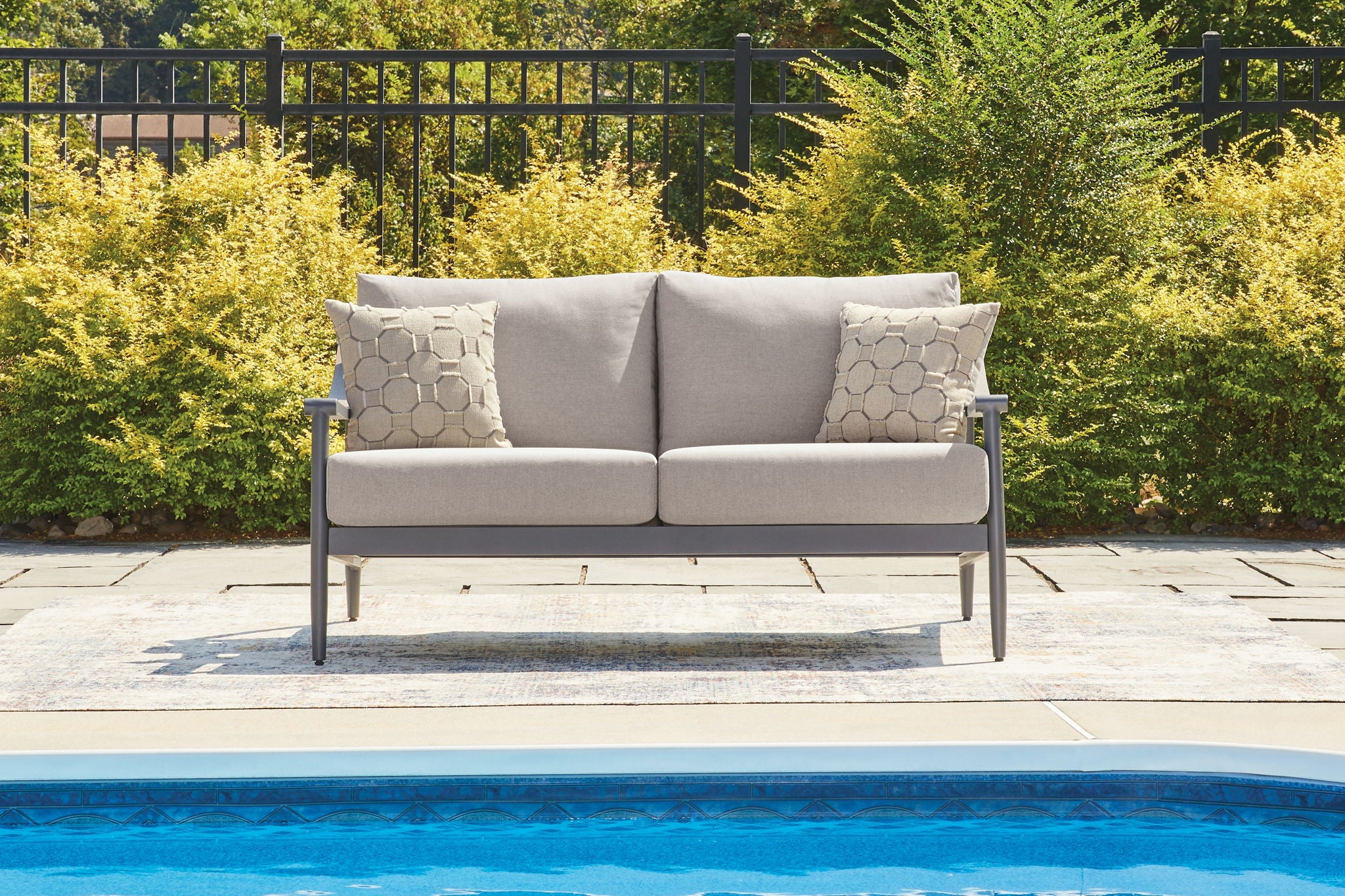 Gray loveseat with seat cushions and four geometric throw pillows