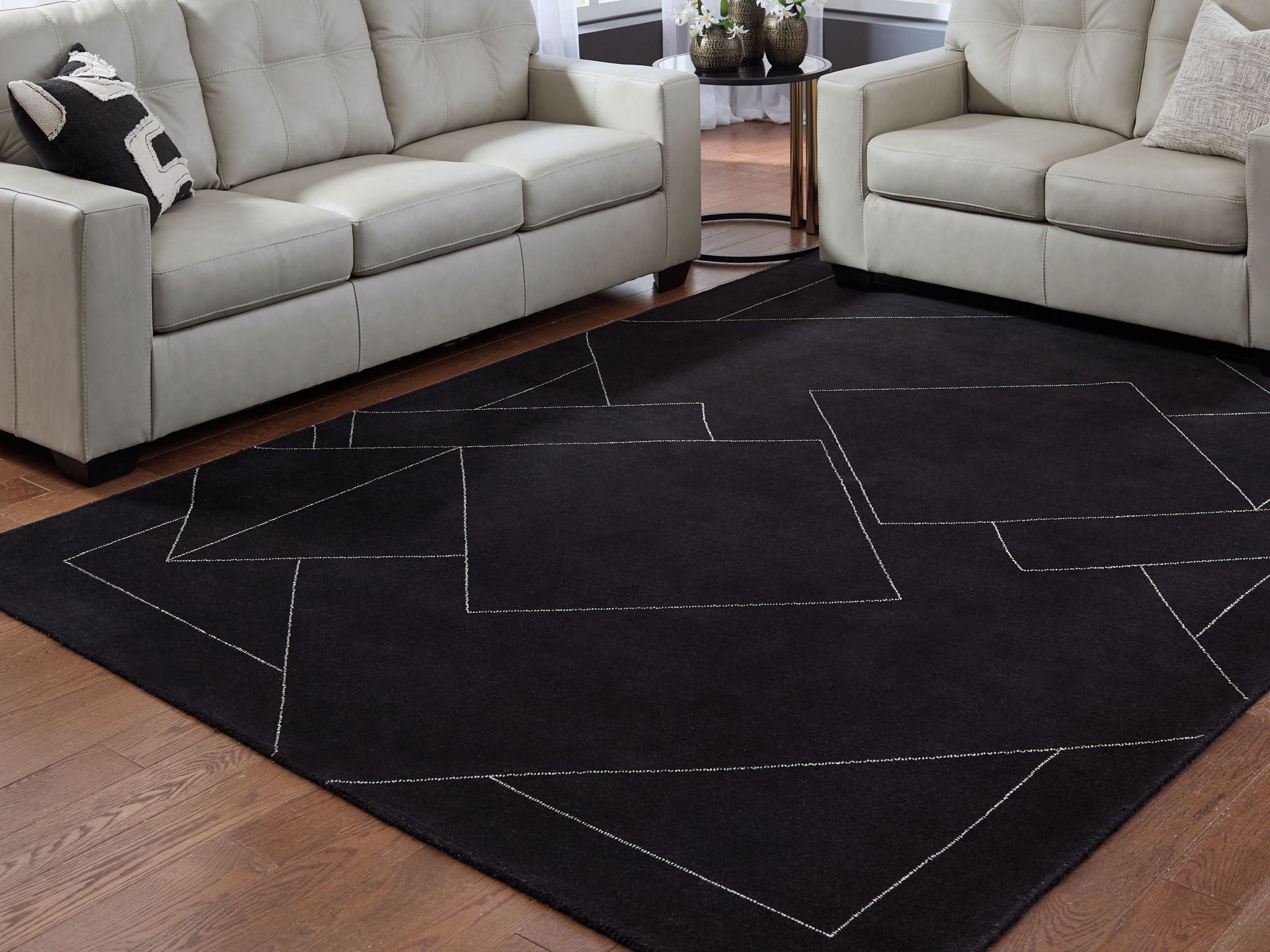 Black geometric area rug with white outlined shapes on hardwood floor