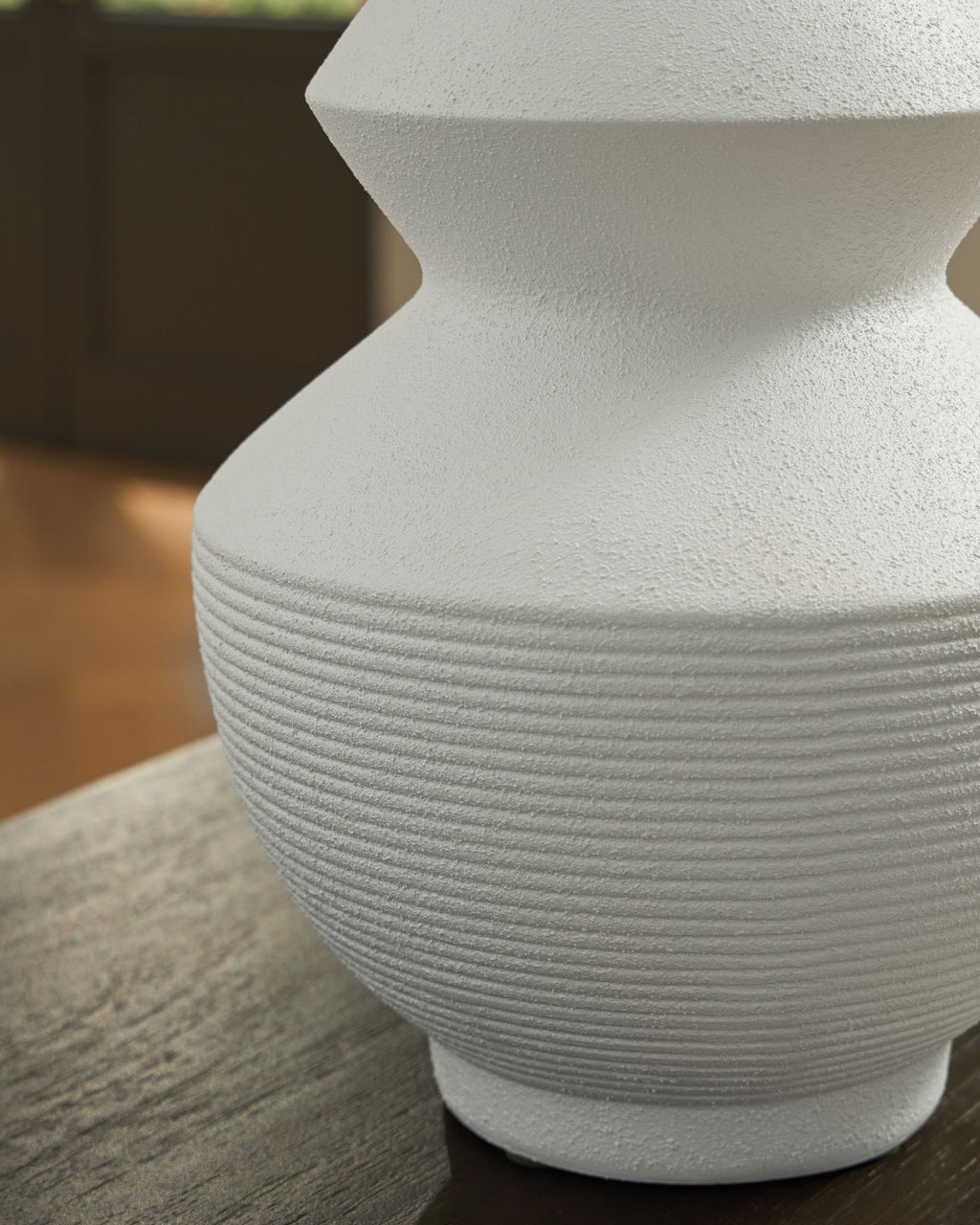 White ceramic vase close-up showing ribbed midsection and flared neck