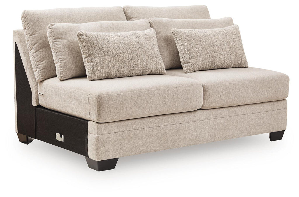 Armless loveseat with light beige fabric, square arms, and two throw pillows