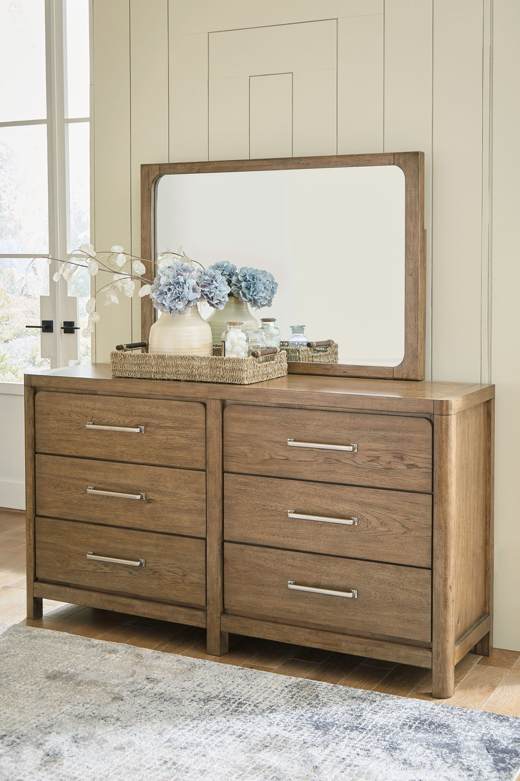 Light brown dresser with large mirror and 6 drawers, styled top with decor